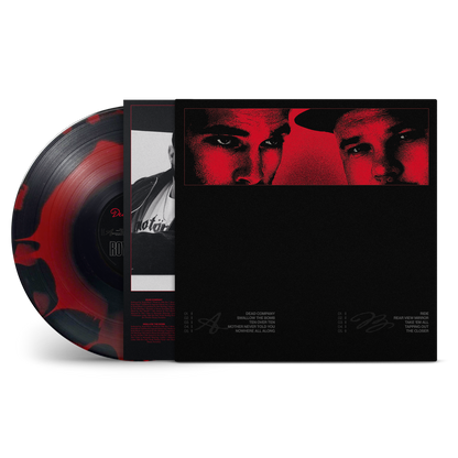 A vinyl record album shown in a clean studio-style product shot. The black record sleeve features a red-and-black portrait of two men, and the vinyl disc itself is partially visible with a red marbled pattern on a black base.