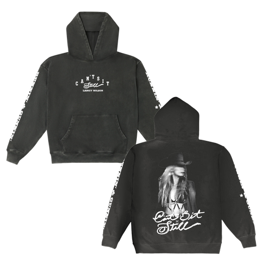 Black hoodie featuring a white graphic print of lainey wilson and the text ‚Äôcan‚Äôt sit still‚Äô on both front and back, with star patterns along the sleeves.
